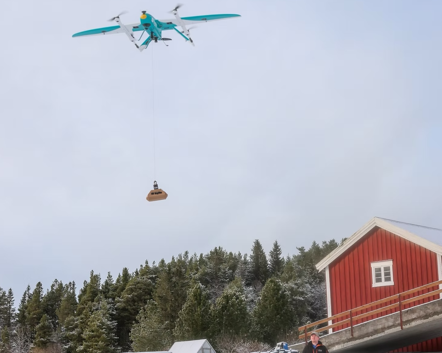 Aviant delivery drone carrying a package over a snowy Norwegian landscape